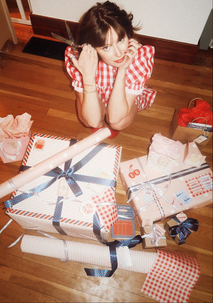 Person sitting on a wooden floor surrounded by wrapped presents